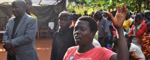 a woman lifts hand in worship with people worshipping behind her