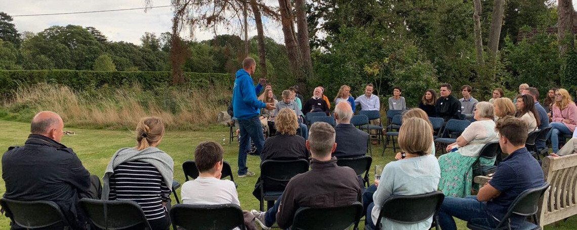 Simon guillebaud speaks to a group of people sat in a garden in the UK