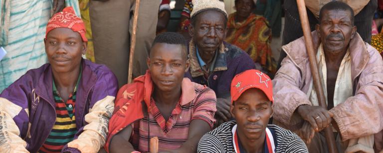 a group of young and old man sit and look into the distance