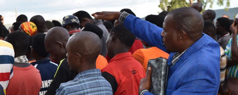 a pastor prays as a group of people worship around him