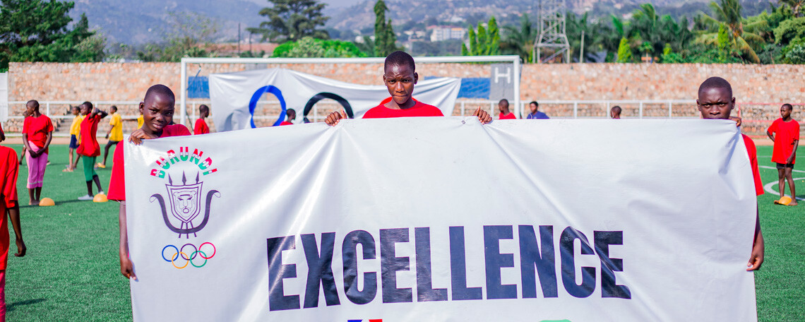 children hold up a banner which says 'excellence'