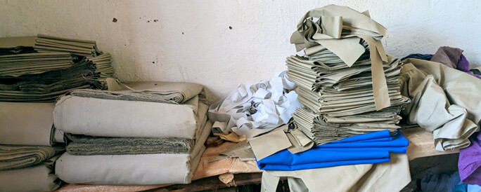 Piles of brown school uniform material folded and ready to sew.